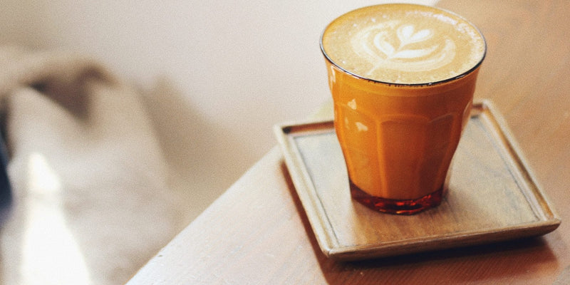 A morning coffee on a timber bench in soft daylight